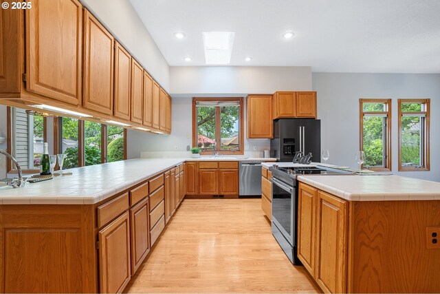 32680 SW Lake Point Ct, Wilsonville, OR 97070 - kitchen with high quality fridge, light wood-style flooring, an island with sink, recessed lighting, and tile countertops