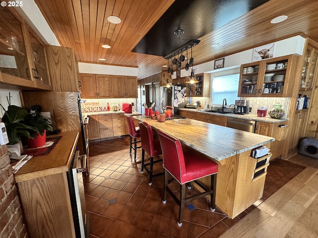 kitchen with appliances with stainless steel finishes, a kitchen island, backsplash, hanging light fixtures, and a breakfast bar area