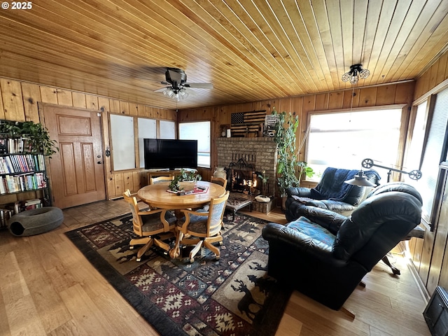 living room featuring wooden ceiling, a healthy amount of sunlight, a brick fireplace, and ceiling fan