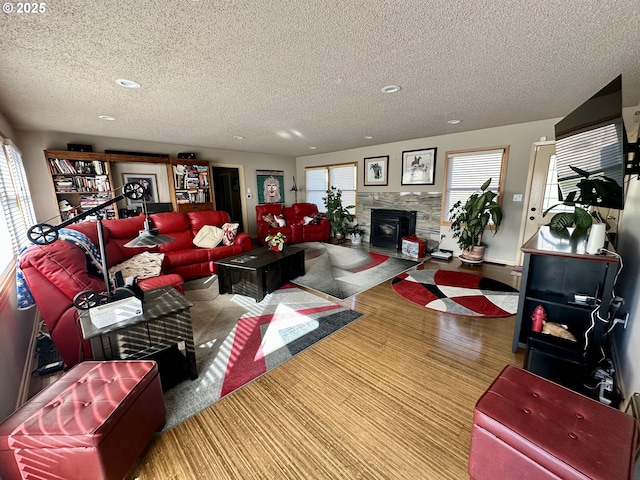 living room featuring baseboard heating, a fireplace, a textured ceiling, and wood-type flooring