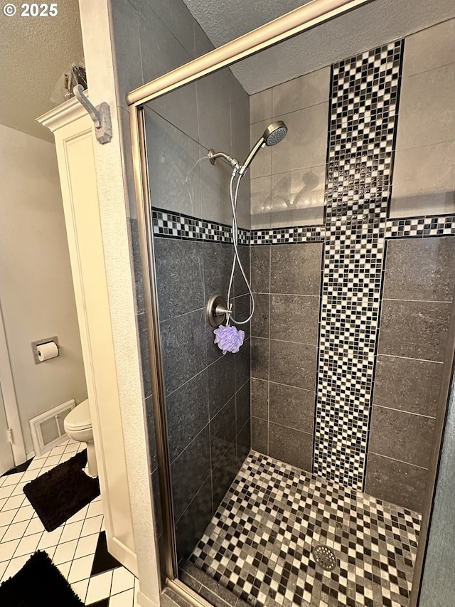 bathroom featuring a shower with shower door, a textured ceiling, tile patterned floors, and toilet