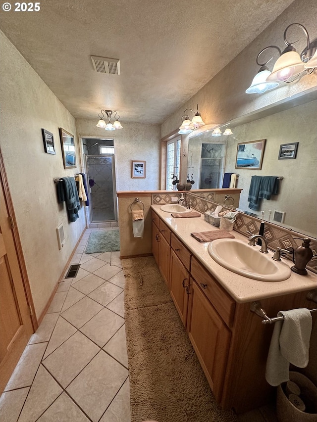 bathroom featuring a textured ceiling, vanity, an inviting chandelier, and tile patterned flooring