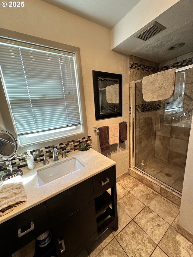 bathroom with decorative backsplash, tile patterned floors, a shower with door, and vanity