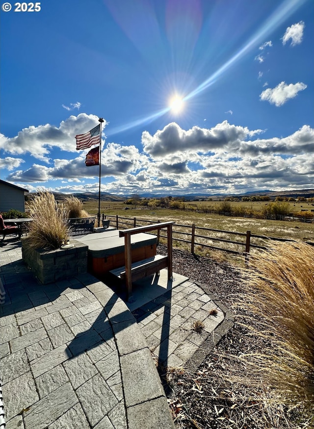 view of patio with a hot tub and a rural view