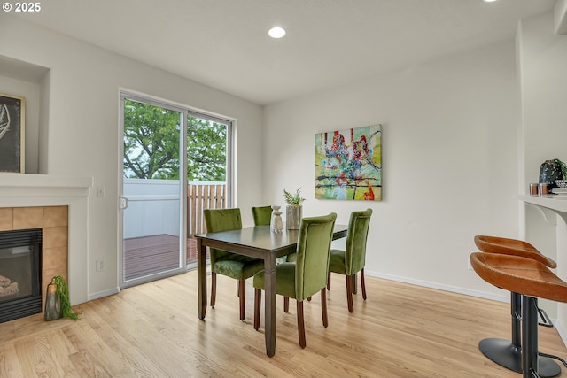 697 NW Rubus Ln, Hillsboro, OR 97124 - dining room featuring light wood-type flooring, baseboards, recessed lighting, and a tiled fireplace