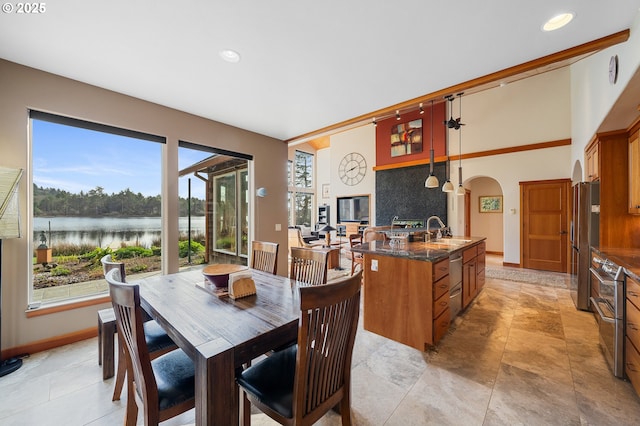 dining space with recessed lighting, baseboards, a water view, and arched walkways