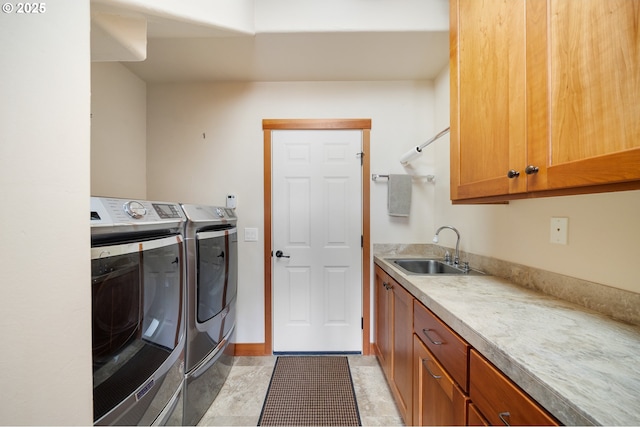 laundry area featuring washing machine and clothes dryer, cabinet space, baseboards, and a sink