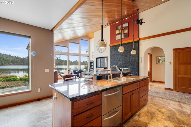 kitchen featuring a warming drawer, a water view, a sink, arched walkways, and baseboards