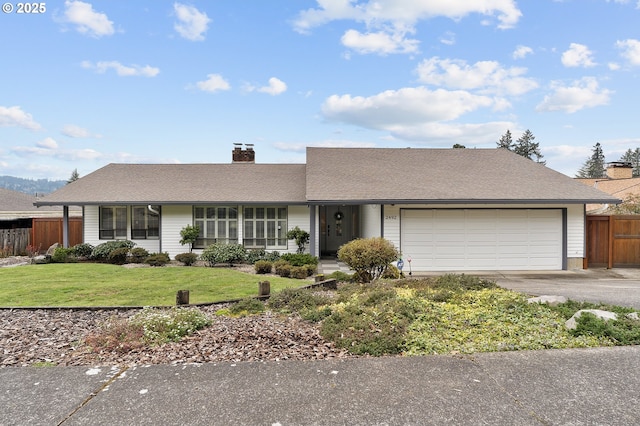 view of front of house with fence, concrete driveway, an attached garage, a front yard, and a chimney