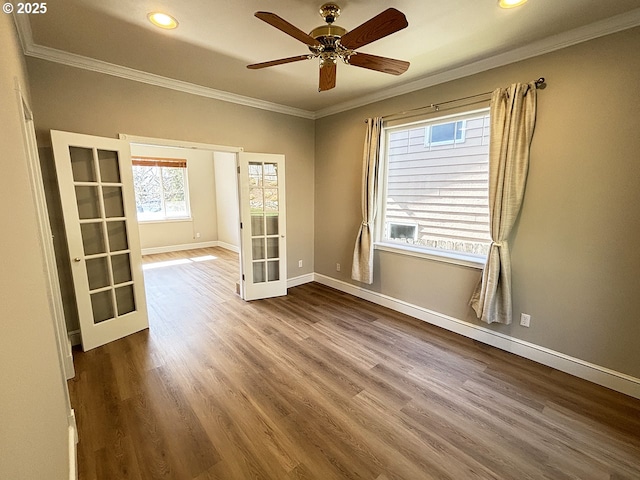 spare room with baseboards, ornamental molding, wood finished floors, and french doors