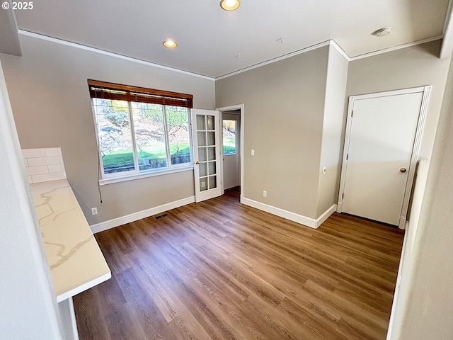 empty room with ornamental molding, wood finished floors, and baseboards