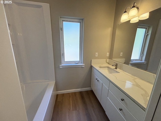 bathroom featuring a tub to relax in, wood finished floors, vanity, baseboards, and walk in shower