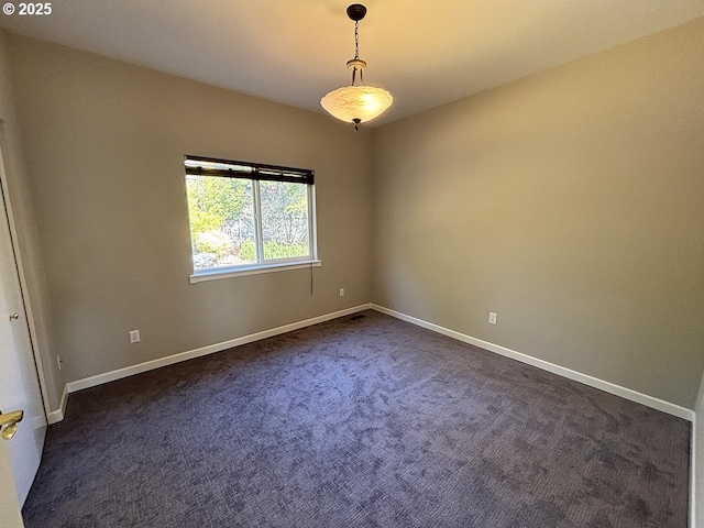 spare room with dark colored carpet and baseboards