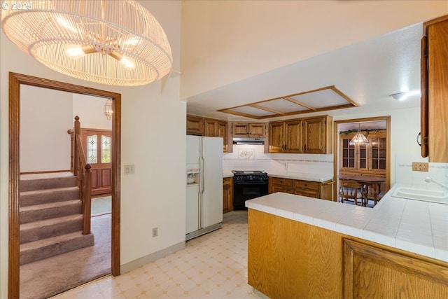 20916 SW Siletz Ct, Tualatin, OR 97062 - kitchen with white refrigerator with ice dispenser, black stove, light flooring, brown cabinets, and tile countertops