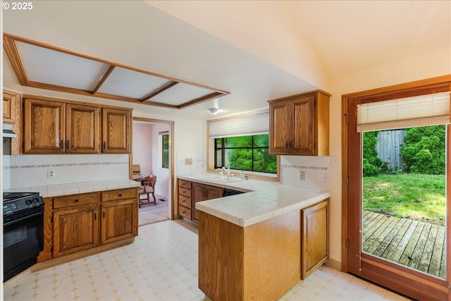 20916 SW Siletz Ct, Tualatin, OR 97062 - kitchen with black range with gas cooktop, healthy amount of natural light, light floors, brown cabinets, and vaulted ceiling