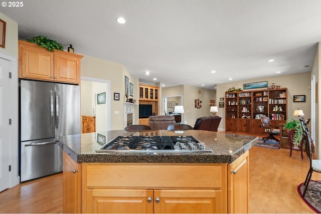 kitchen with light wood-type flooring, a center island, stainless steel appliances, open floor plan, and tile counters