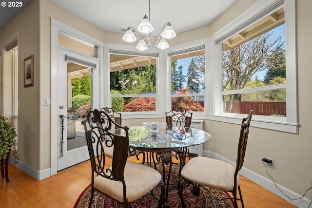 dining space featuring baseboards, light wood-type flooring, and an inviting chandelier
