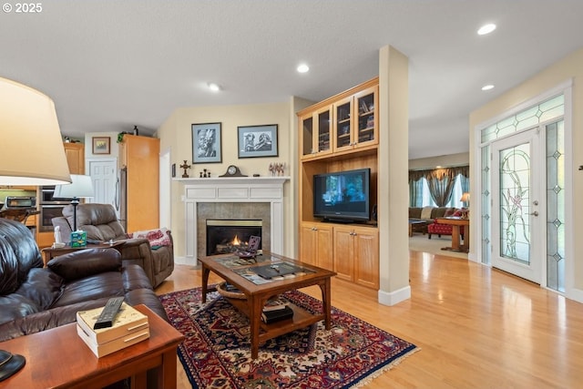 living room with recessed lighting, light wood-type flooring, a toaster, and a tile fireplace