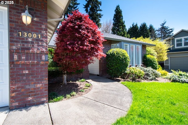 view of exterior entry featuring brick siding and a garage