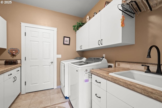 laundry room with light tile patterned floors, washing machine and dryer, a sink, and cabinet space