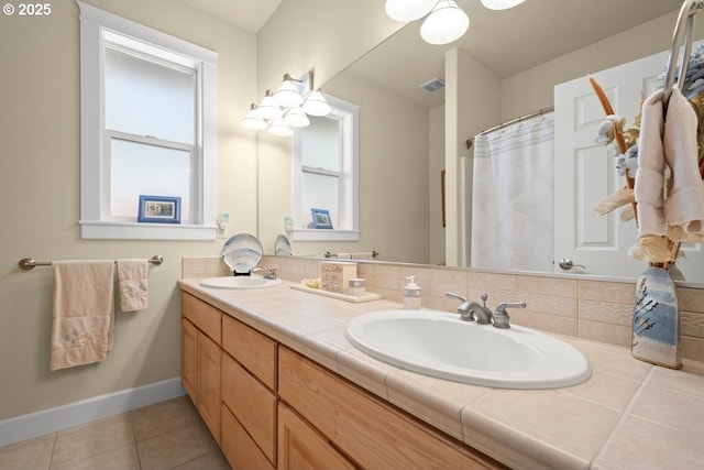 bathroom with a sink, baseboards, double vanity, and tile patterned flooring