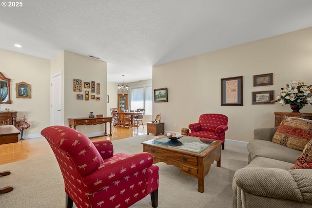 living area featuring light colored carpet, visible vents, recessed lighting, baseboards, and a notable chandelier