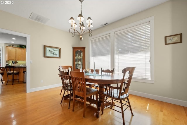 dining area with a chandelier, light wood finished floors, visible vents, and baseboards