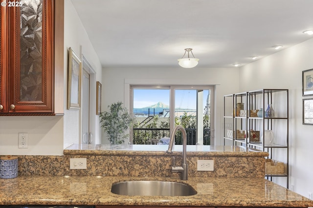 kitchen with light stone countertops, a mountain view, and sink