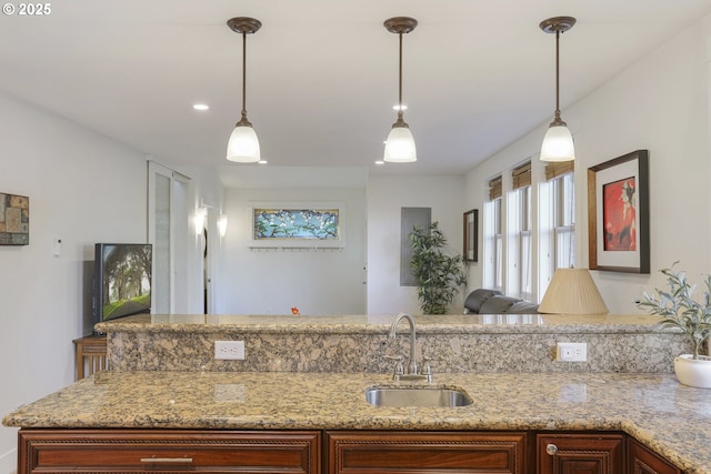 kitchen with sink, decorative light fixtures, and light stone countertops