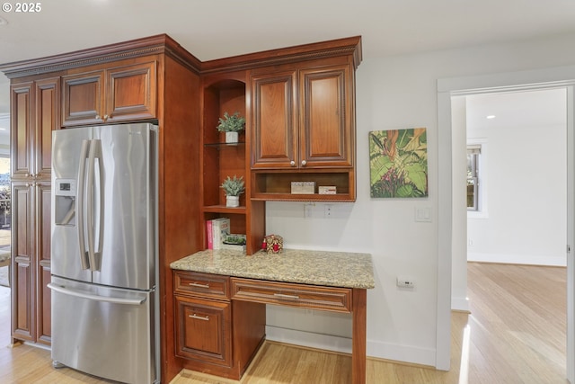 kitchen featuring stainless steel fridge, light wood-type flooring, and light stone counters