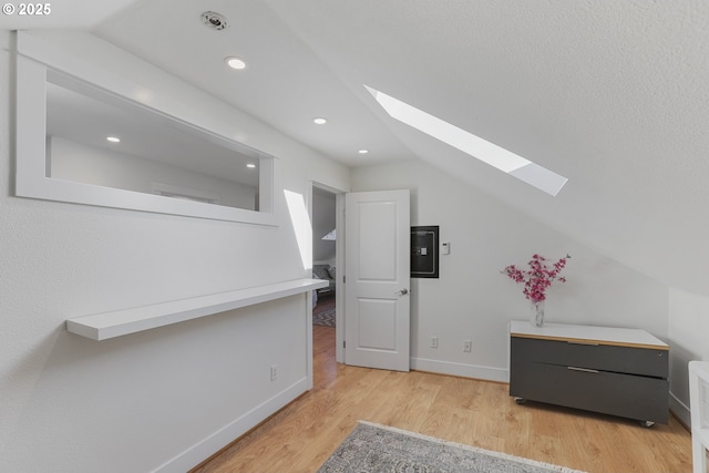 interior space with lofted ceiling with skylight and light hardwood / wood-style floors