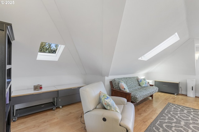 sitting room with vaulted ceiling with skylight and light hardwood / wood-style flooring