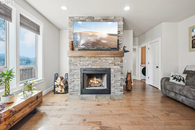 living area with recessed lighting, a stone fireplace, and wood finished floors