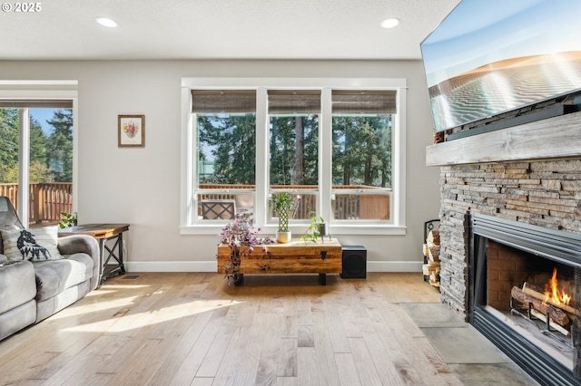living area featuring light wood-style flooring, recessed lighting, baseboards, and a fireplace