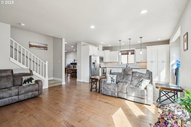 living area featuring light wood-style flooring, recessed lighting, baseboards, and stairs