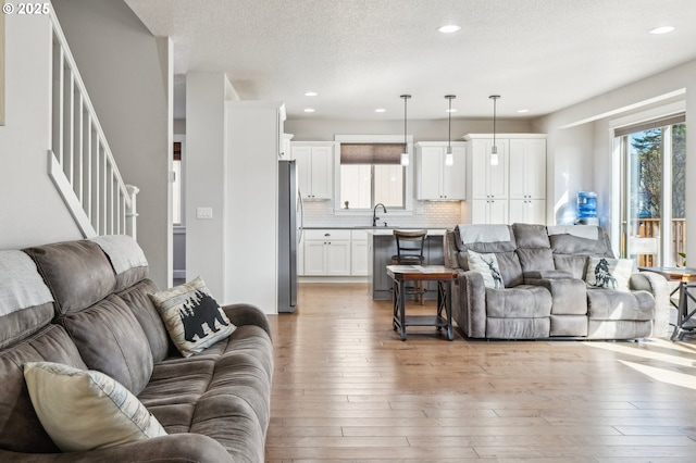 living room featuring light wood-type flooring, recessed lighting, stairway, and a textured ceiling