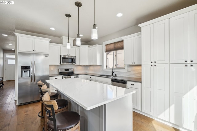 kitchen featuring a center island, appliances with stainless steel finishes, a sink, and backsplash