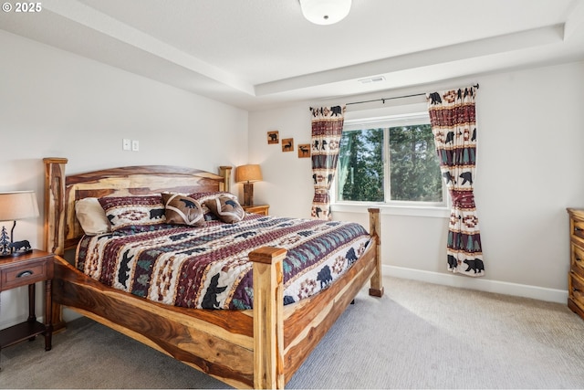 bedroom with a raised ceiling, carpet flooring, baseboards, and visible vents