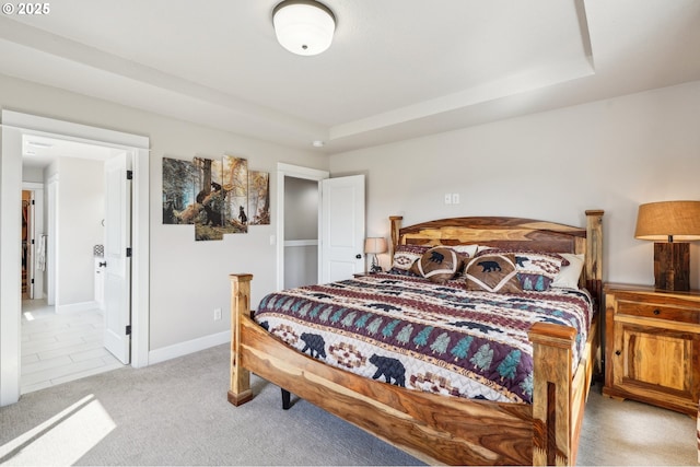 carpeted bedroom featuring baseboards and a raised ceiling