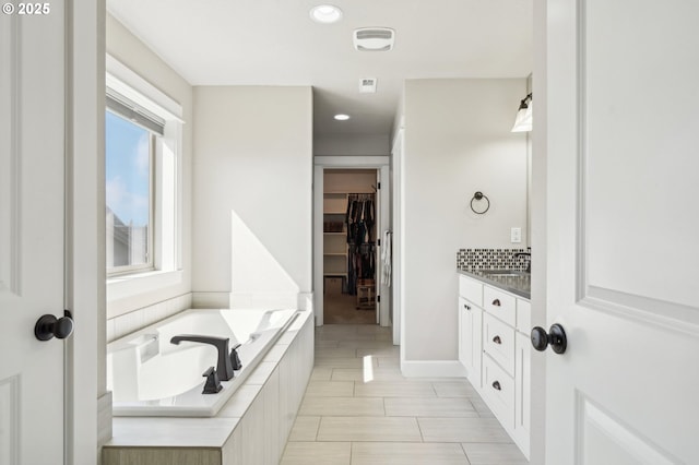 full bath with a bath, vanity, visible vents, recessed lighting, and a walk in closet
