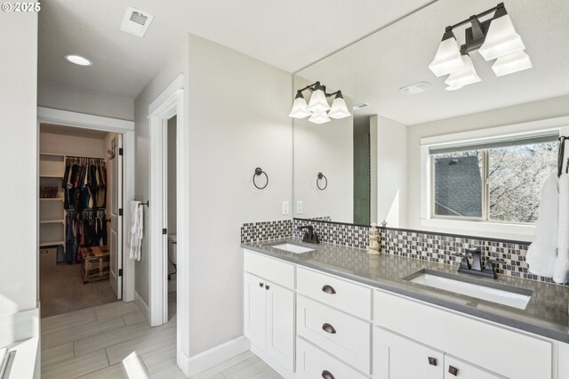 full bath with double vanity, decorative backsplash, a sink, and visible vents
