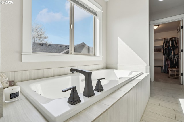 full bath featuring a spacious closet and tiled tub