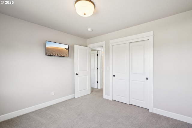 unfurnished bedroom with a closet, baseboards, and light colored carpet