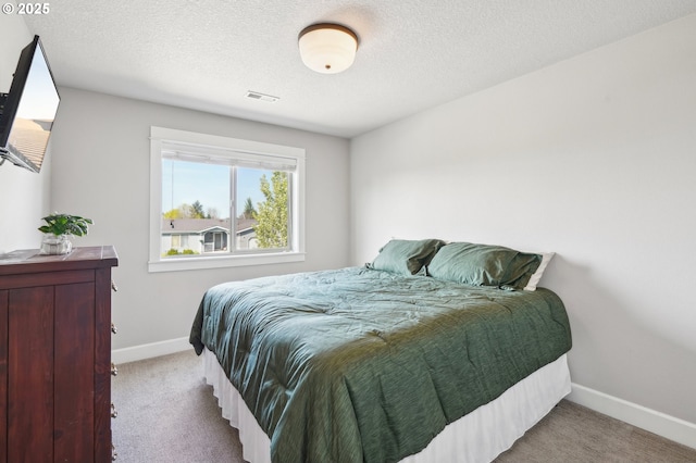 carpeted bedroom featuring a textured ceiling, baseboards, and visible vents