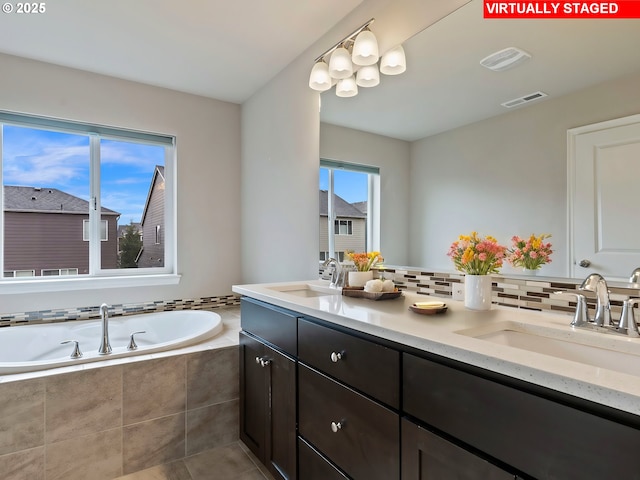 bathroom featuring vanity, backsplash, and tiled bath