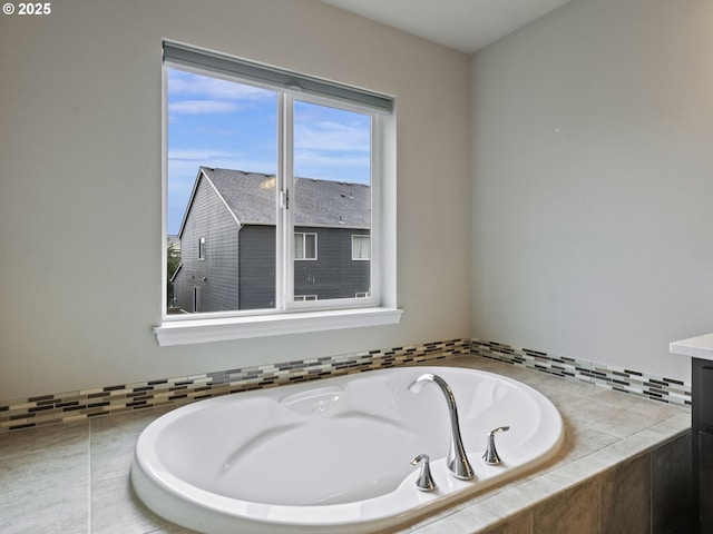 bathroom featuring a relaxing tiled tub and vanity