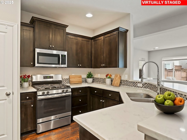 kitchen featuring stainless steel appliances, sink, dark wood-type flooring, and dark brown cabinetry