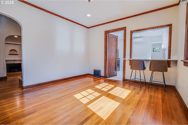 unfurnished room featuring crown molding, a large fireplace, sink, and light wood-type flooring