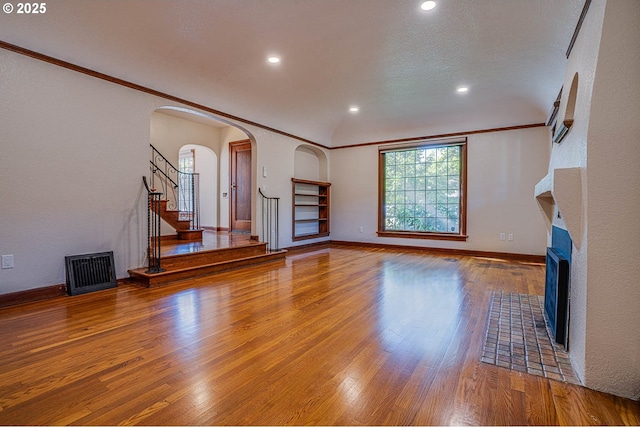 unfurnished living room featuring lofted ceiling, hardwood / wood-style flooring, crown molding, and a textured ceiling