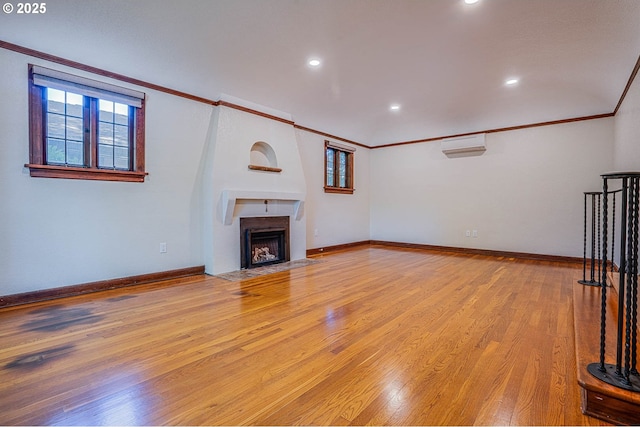 unfurnished living room with ornamental molding, a wall unit AC, and light wood-type flooring